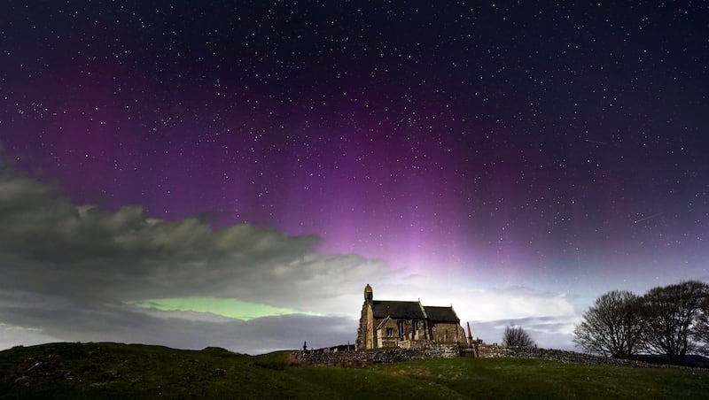 The aurora borealis, also known as the Northern Lights, illuminate the sky just before midnight over St Aidan's Church in Thockrington, Northumberland. PA