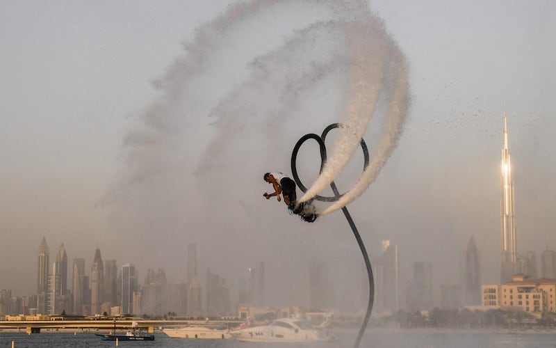 TOPSHOT - An athlete performs stunts with a water jet pack on the first day of the Dubai watersport festival, organised by the Dubai International Marine Club (DIMC), near the Burj Khalifa skyscraper in the Gulf emirate on June 25, 2020.  / AFP / KARIM SAHIB
