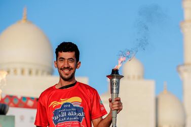 A torch runner proudly holds up the torch infront of the Abu Dhabi Grand Mosque during a practice run last year. Victor Besa / The National