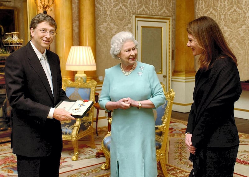 Britain's Queen Elizabeth II presents Microsoft tycoon Bill Gates with his honorary knighthood at Buckingham Palace, London, Wednesday March 2, 2005 watched by his wife Melinda. Gates, one of the richest men in the world, cannot use the title "Sir" as he is not a British citizen. He received the KBE insignia, in recognition of his charitable donations in Commonwealth countries.      AFP PHOTO/CHRIS YOUNG/WPA POOL (Photo by CHRIS YOUNG / POOL / AFP)