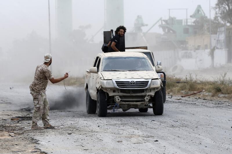 Fighters drive past the spot where a mortar had just hit during clashes. AFP
