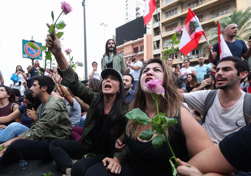 TOPSHOT - Lebanese actress and film director Nadine Labaki (C) holds a rose as she takes part with fellow demonstrators in an anti-government protest on a major bridge in the centre of the capital Beirut on October 26, 2019.  An unprecedented, cross-sectarian protest movement demanding the removal of an entrenched political elite has paralysed the country since October 17. / AFP / STR
