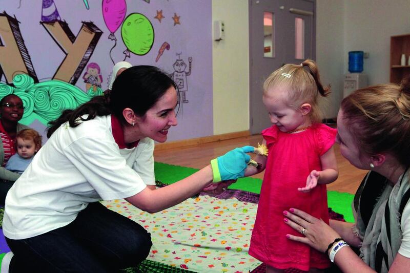 Teacher of baby Arabic Sawsan Al Azen, left, interacts with 22-month-old French baby Naomi Sofia Catto. Jeffrey E Biteng / The National