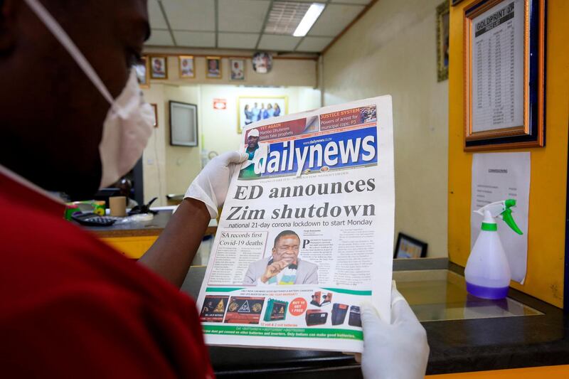 A man wearing a facemask and latex gloves reads a copy of a daily newspaper in Harare, Zimbabwe.  EPA