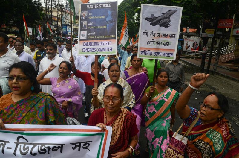 Indian Congress activists walk at a rally holding placards against the Rafale jets deal during a nationwide 'Bharat Bandh' strike called by main opposition parties against a fuel price hike in Siliguri on September 10, 2018. - India's opposition parties led by the Indian National Congress organised nationwide strikes and protests over rising fuel prices, looking to tap into public anger against Prime Minister Narendra Modi's government ahead of a key general election next year. (Photo by DIPTENDU DUTTA / AFP)