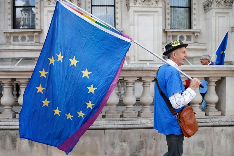 epa07729377 An Anti Brexit protester with EU flags takes part in the No to Boris, Yes to EU March in London, Britain, 20 July 2019. Thosuands of people gathered to march against Brexit and Boris Johnson to likely be named as the new British Prime Minister.  EPA/HOLLIE ADAMS
