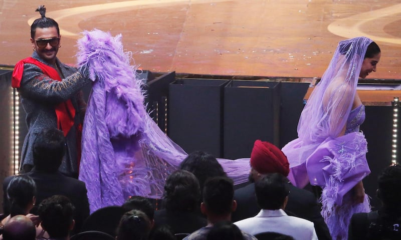 Ranveer Singh, left, carries the back of his wife and actress Deepika Padukone's dress during the event. AFP