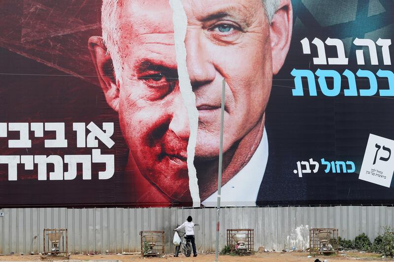A boy looks up at a Blue and White party election campaign banner depicting its leader, Israeli Defence Minister Benny Gantz, alongside Israeli Prime Minister Benjamin Netanyahu, in Bnei Brak. Reuters