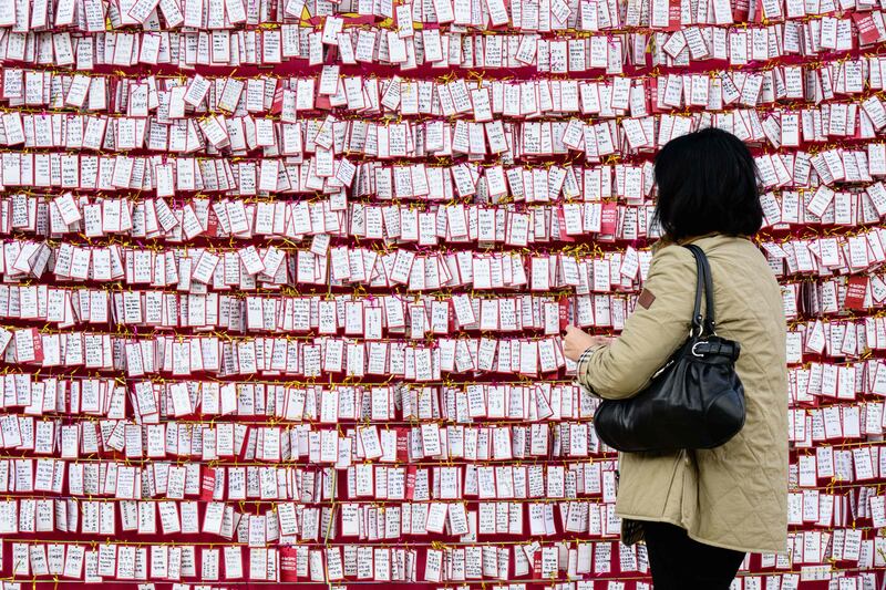 A woman adds a handwritten note to a display as prayers take place at the Jogyesa Buddhist temple for the success of children who at the same time were sitting the annual nine-hour college entrance exam in Seoul. South Korea closed its airspace to ensure silence and offered police escorts for tardy test takers on November 17 as more than half a million pupils sat high-stakes college admission exams. AFP