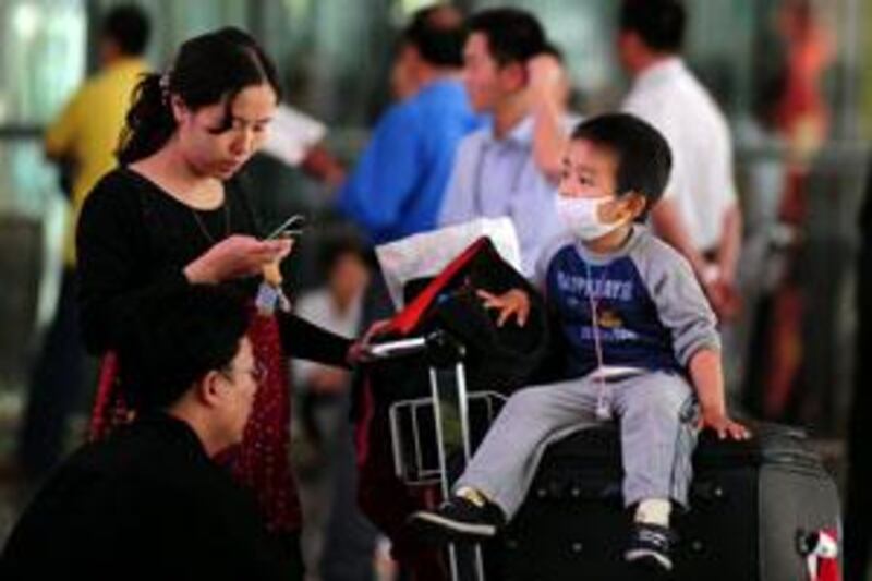 A child travelling with his parents wears a protective face mask at the airport in Beijing on June 9 2009.