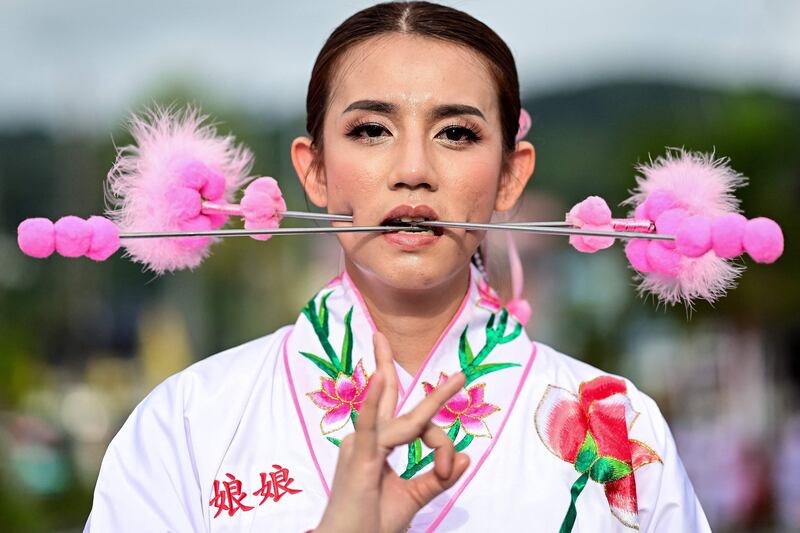 A devotee of the Jor Soo Gong Naka shrine with skewers pierced through her cheeks takes part in a procession during the annual Vegetarian Festival in Phuket, Thailand. AFP