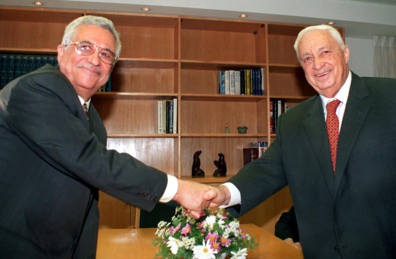 Mahmoud Abbas (L), the Palestinian negotiator better known as Abu Mazen, and Israeli Foreign Minister Ariel Sharon turn to the cameras and smile as they shake hands at the start of their meeting in Sharon's office November 18. The two met to review the work of all the Israeli-Palestinian peace committees and to set a date for the resumption of final status talks.

DPS/KM