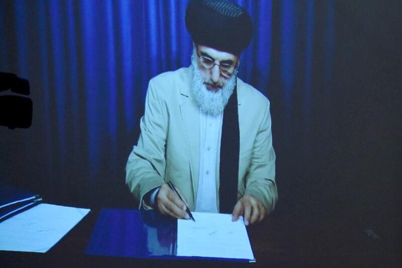 Gulbuddin Hekmatyar is displayed on a video projector screen as he signs a peace deal with Afghan president Ashraf Ghani on September 29, 2016. Wakil Kohsar/AFP