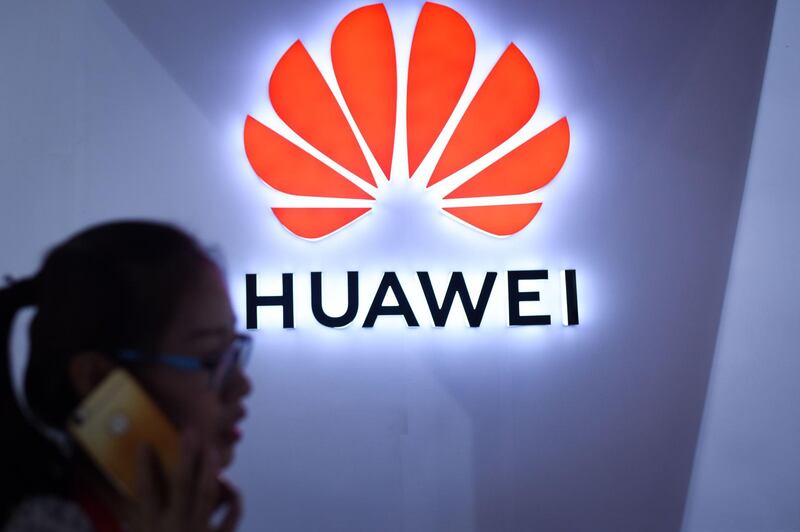 (FILES) In this file photo taken on July 08, 2018 (FILES) In this file photo taken on July 8, 2018 a woman uses her mobile phone in front of a Huawei logo at Beijing International Consumer Electronics Expo in Beijing. Chinese telecom giant Huawei's chief financial officer faces US fraud charges related to sanctions-breaking business dealings with Iran, a Canadian court heard on December 7, 2018, a week after she was detained on an American extradition request. / AFP / WANG ZHAO
