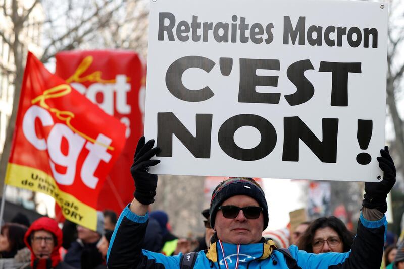 A demonstrator holds a placard which reads "No to Macron's pensions reform" during a demonstration against French government's pensions reform plans in Paris as part of another day of nationwide strikes and protests in France, January 24, 2020.  REUTERS/Christian Hartmann