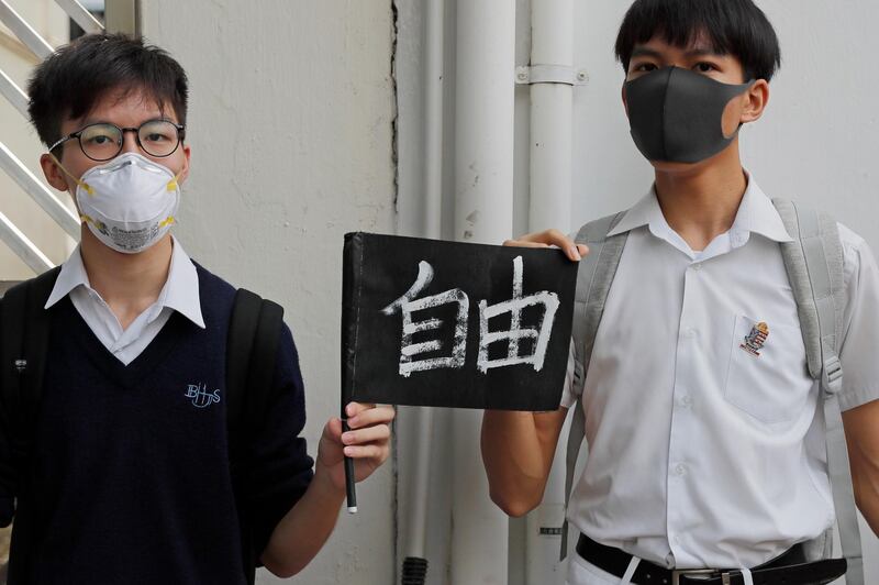 Students hold a placard reads "Freedom" as they form human chain outside a school in Hong Kong