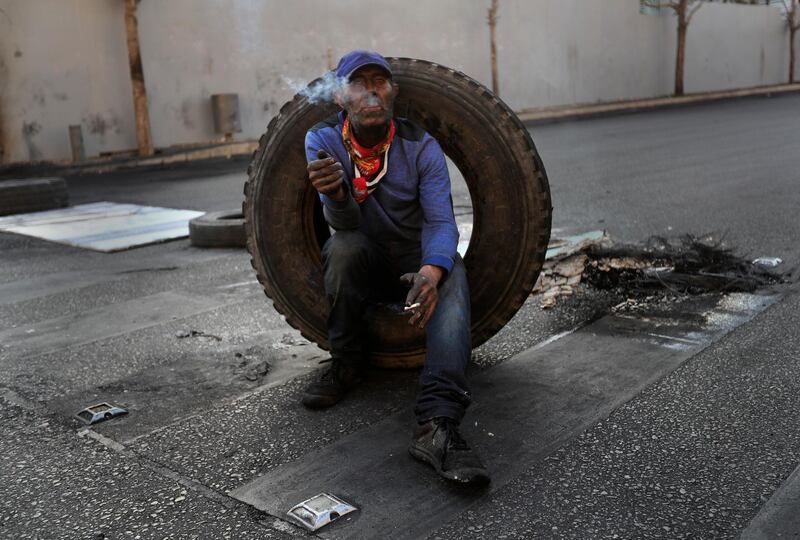 A protester smokes a cigarette as he aims to block a road during a protest in Beirut. AP Photo
