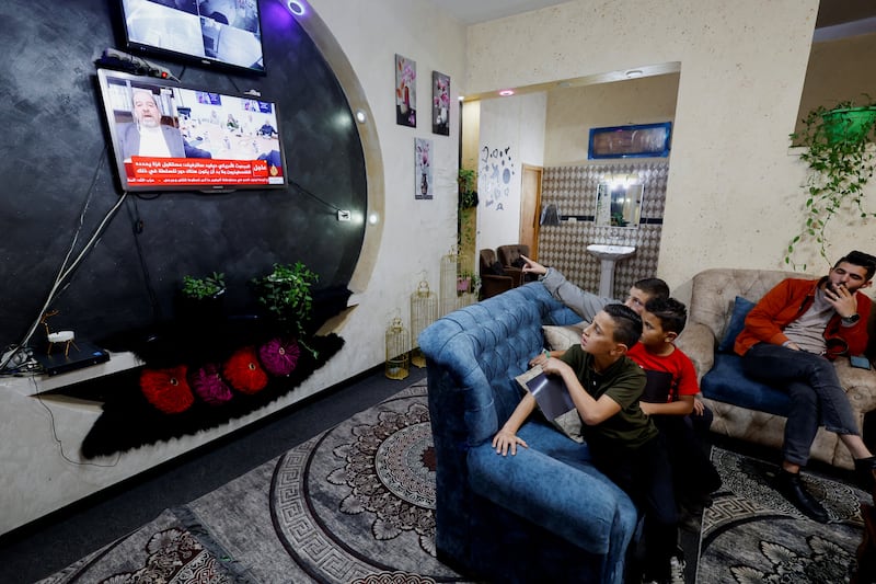 A family watch news updates on the Israeli hostages and Palestinian prisoners swap deal, near Hebron in the Israeli-occupied West Bank. Reuters
