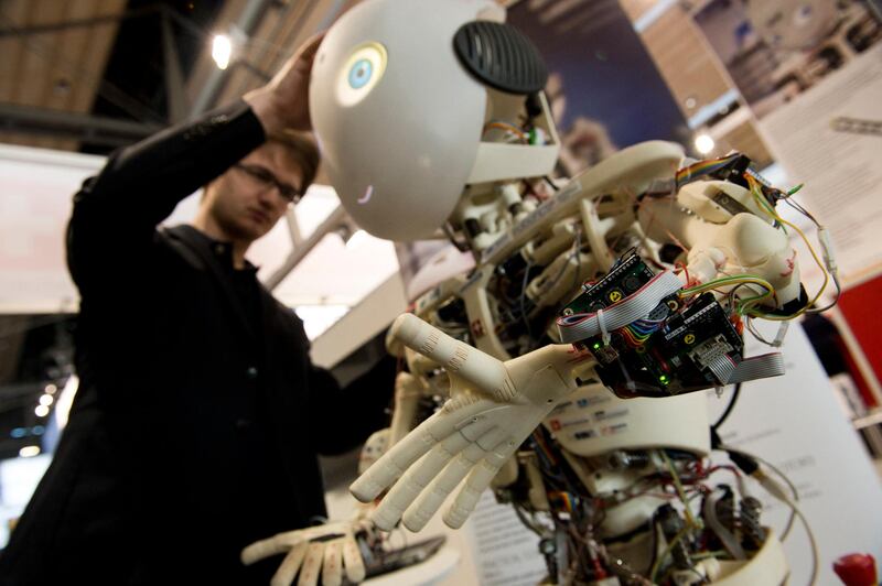 Artificial intelligence engineer- An engineer looks over Roboy, a humanoid robot developed at the Artificial Intelligence Laboratory of the University of Zurich, at the 2014 CeBIT technology trade fair on March 9, 2014 in Hanover, central Germany. Standing at 1.2 m (3.9 ft), Roboy is designed to have the appearance of a child and to one day be used as a helper robot for the sick and elderly. Unlike more traditional robots, which have motors in their joints, Roboy is a tendon-driven robot, allowing for more fluent, human-like movements. Great Britain is partner country of the fair considered as the world's biggest high-tech fair running from March 10 to 14, 2014.      AFP PHOTO / JOHN MACDOUGALL (Photo by JOHN MACDOUGALL / AFP)