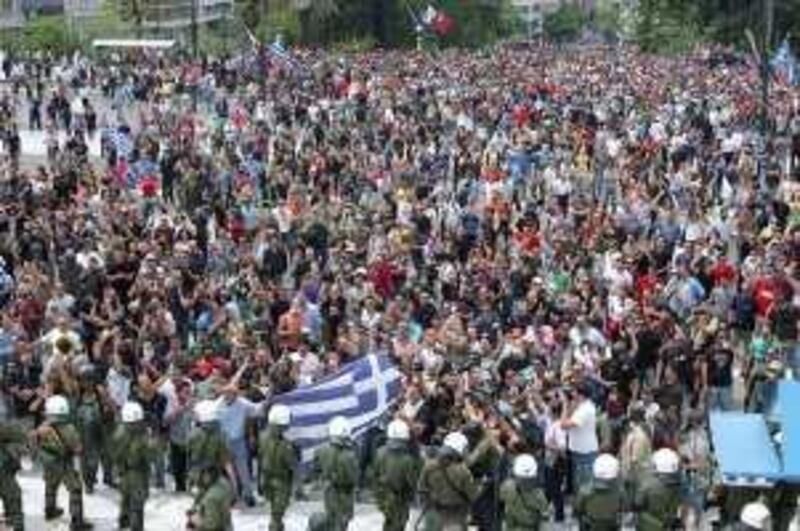 epa02144557 Greek protesters hold the Greek national flag as they face riot police during a demonstration against the new tough austerity measures of the government, outside the Greek Parliament in Athens, Greece, 05 May 2010. Three people died on 05 May when a bank was set ablaze as tens of thousands of Greek demonstrators took to the streets to protest government austerity measures in exchange for an international bailout aimed at saving the country from bankruptcy.  The bodies of two men and a woman were discovered inside the bank branch of Marfin, located in downtown Athens while at least 20 people were hospitalised with injuries.  EPA/PANTELIS SAITAS *** Local Caption ***  02144557.jpg *** Local Caption ***  02144557.jpg