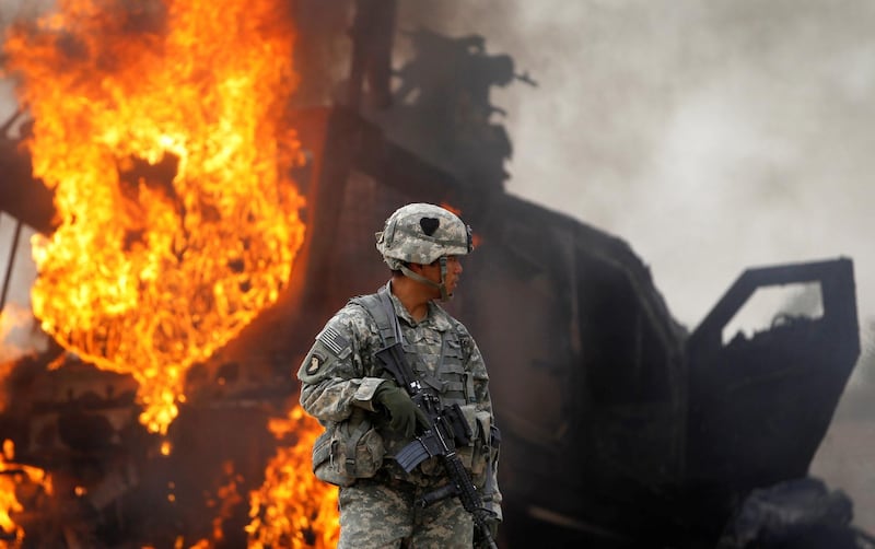 Captain Melvin Cabebe with the US Army's 1-320 Field Artillery Regiment, 101st Airborne Division stands near a burning M-ATV armored vehicle after it struck an improvised explosive device near Combat Outpost Nolen in the Arghandab Valley north of Kandahar, Afghanistan, July 23, 2010. Reuters