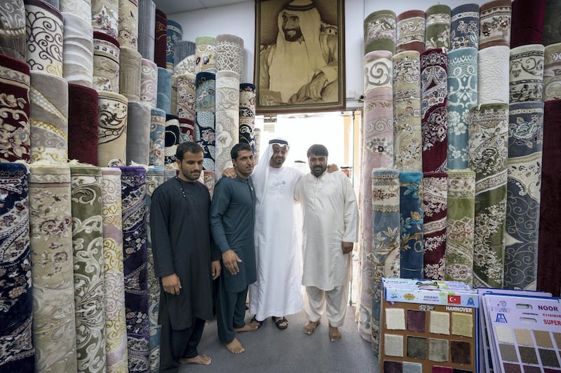 ABU DHABI, UNITED ARAB EMIRATES -  February 22, 2018: HH Sheikh Mohamed bin Zayed Al Nahyan, Crown Prince of Abu Dhabi and Deputy Supreme Commander of the UAE Armed Forces (3rd L), stands for a photograph with staff at Al Safa Carpet shop, in the carpet market of the Mina Zayed Port. 
( Ryan Carter for the Crown Prince Court - Abu Dhabi )
---
