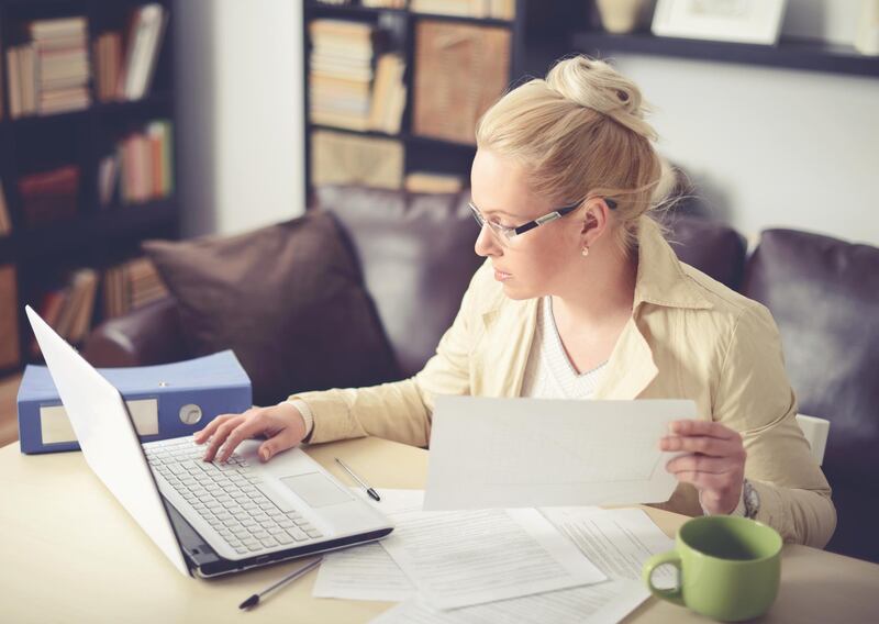 beautiful woman sitting at the table and working at home. Getty Images