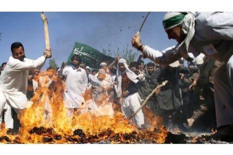 Afghan protesters beat a burning effigy of Barack Obama, the US president, in the eastern city of Jalalabad yesterday.