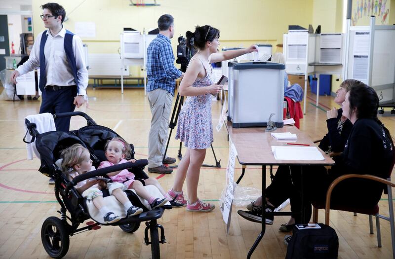 A woman votes while her children wait in their pushchair as Ireland holds a referendum on liberalizing its law on abortion, in Dublin, Ireland, May 25, 2018. REUTERS/Max Rossi