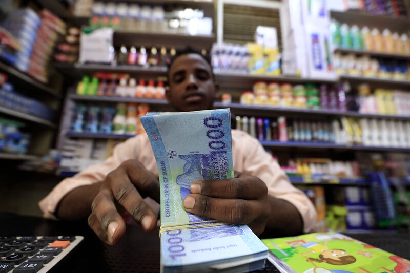 A Sudanese grocery shop owner counts money in the capital Khartoum. Sudan is facing debt distress and rising inflation as food shortages worsen its economic crisis. AFP