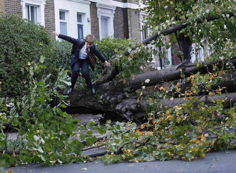 Theo Harcourt, a 13-year-old schoolboy, jumps over a fallen tree as he makes his way to school in Islington, north London. Strong winds and rain battered southern parts of England and Wales early on Monday, forcing flight cancellations, disrupting trains and closing roads and major bridges before the start of rush-hour traffic. Olivia Harris / Reuters