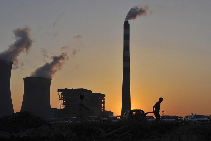 A worker pulls a cart in front of the smoking chimneys of a power plant in Hefei, Anhui province, on October 24, 2014. China's economy, the world's second largest, grew at its slowest pace since the global financial crisis in the September quarter and risks missing its official target for the first time in 15 years, stoking worries about global growth as well as the risk of social discontent. Reuters