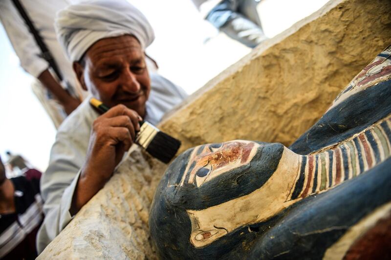 A man brushes off dust from a sarcophagus, part of a new discovery at Dahshur necropolis. AFP
