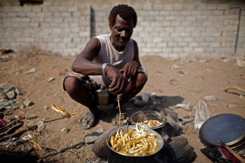 A man from the Akhdam community cooks chicken feet outside his hut in Houdieda.