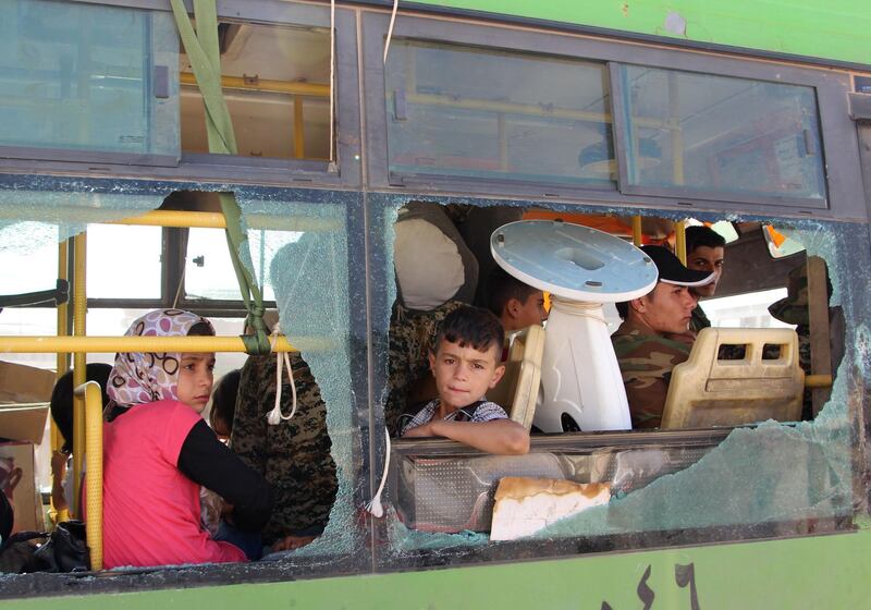 CORRECTION / Evacuated Syrians from  the area of Fuaa and Kafraya in the Idlib province, look out of a broken bus window as it passes the al-Eis crossing south of Aleppo during the evacuation of several thousand residents from the two pro-regime towns in northern Syria on July 19, 2018.  As the buses passed through rebel-held territory, people threw rocks at them, which shattered the windows during the evacuation which put an end to one of the longest sieges of the country's seven-year civil war. Fuaa and Kafraya were the last remaining areas under blockade in Syria and a rare example of pro-government towns surrounded by rebel forces. / AFP / Ibrahim YASOUF
