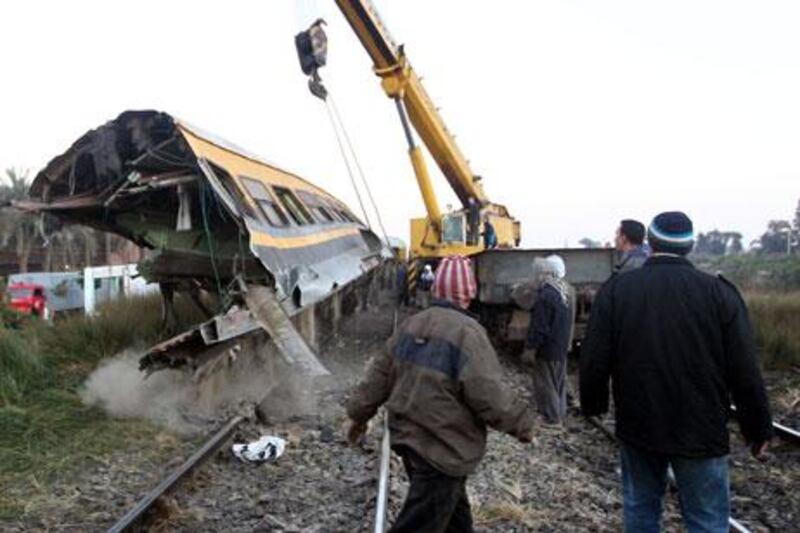 Rescue workers lift a railcar at the site where a train transporting soldiers crashed in the Giza neighbourhood of Badrashin on Tuesday. Khaled Elfiqi / EPA