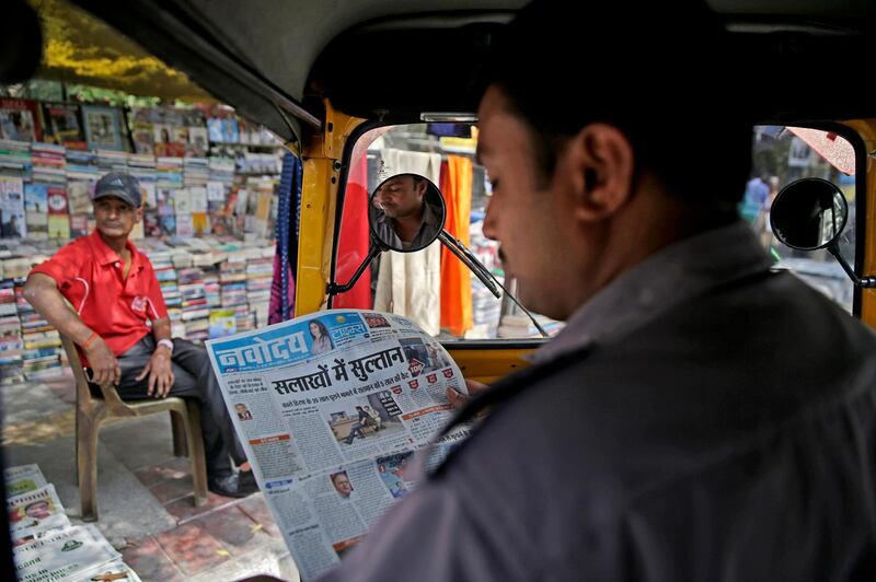 An Indian auto-rickshaw driver reads a Hindi newspaper with a headline about the conviction of Bollywood star Salman Khan. Altaf Qadri / AP Photo