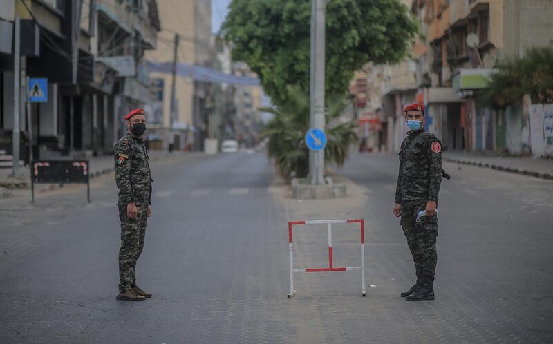 Palestinian policemen stand guard in an empty street during a complete closure amid the pandemic in Gaza City.  EPA