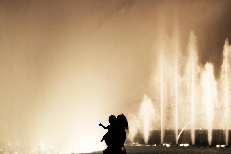 DUBAI , UNITED ARAB EMIRATES , December 18 – 2020 :- Mother with her daughter watching the Dubai Fountain from the Burj Park in downtown Dubai in Dubai. ( Pawan Singh / The National ) For Standalone/Big Picture/Instagram