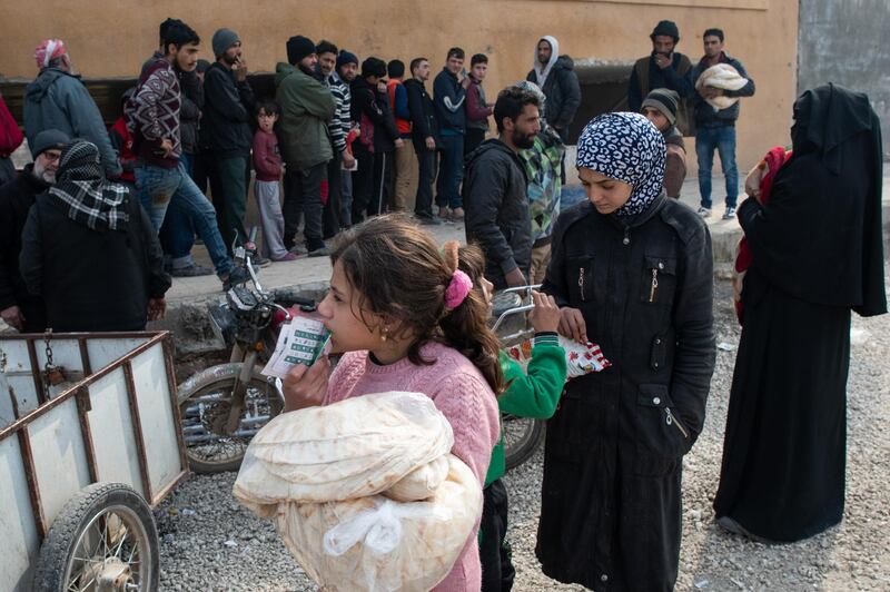 A displaced Syrian girl carries a bag of bread in a stadium which has been turned into a makeshift refugee shelter in Idlib, Syria.  Getty