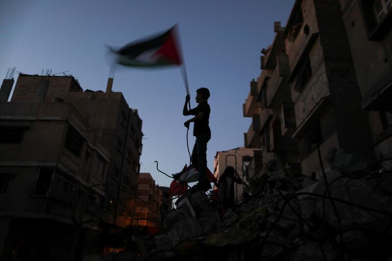 A boy waves a Palestinian flag at a site damaged by Israeli air strikes in Gaza. Reuters