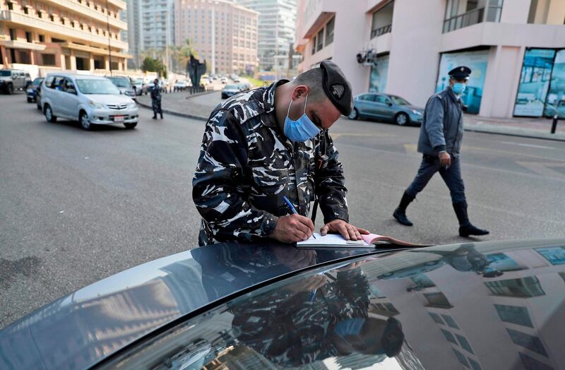 A Lebanese policeman in Antelias books a driver for violating the coronavirus lockdown. AFP