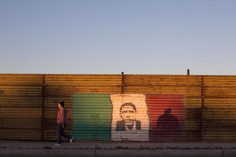 A woman walks next to a painting of former US president Barack Obama at the US-Mexico border fence in San Luis Rio Colorado, Sonora state, Mexico. Guillermo Arias / Agence France-Presse / February 15, 2017