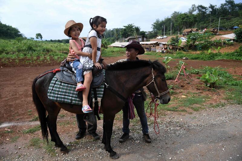 Girls riding a pony on the road leading to the Tham Luang cave. AFP