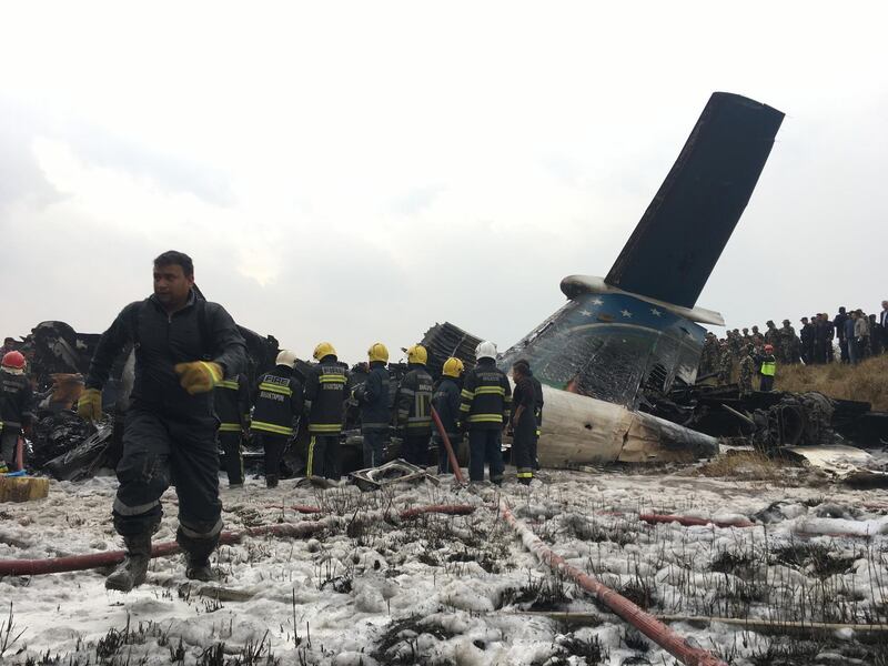 Nepalese rescuers stand near a passenger plane from Bangladesh that crashed at the airport in Kathmandu, Nepal. Niranjan Shreshta / AP Photo