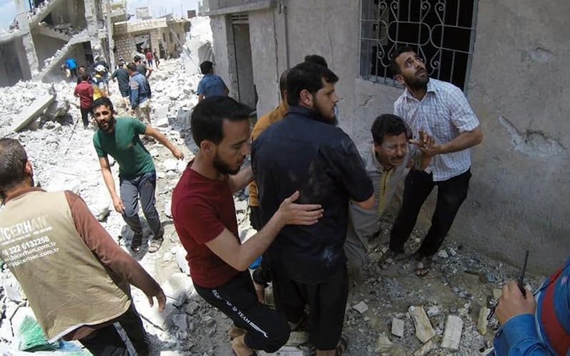 Syrians gathering at the scene where an airstrike by government forces hit the town of Jabal al-Zawiya in Idlib province. AP