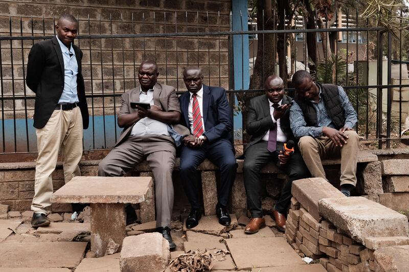 People listen to the broadcast of the Supreme Court of Kenya's judgment on the outcome of the general election on their smart phones in Nairobi. AFP