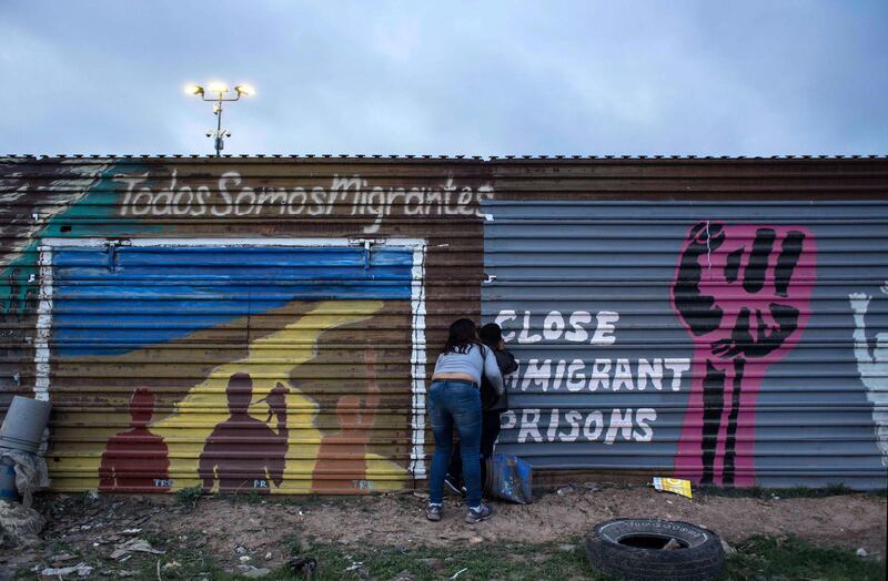 A woman and a child in Tijuana, Mexico, peep through a hole in the fence dividing Mexico and the US to have a look at the prototypes of the wall US President Donald Trump wants to build on the border. Guillermo Arias / AFP