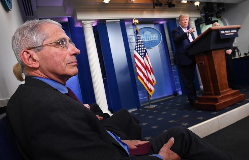 epa08356410 President Donald J. Trump stands as Dr. Anthony Fauci, Director of the National Institute of Allergy and Infectious Diseases at the National Institutes of Health, listens during a Coronavirus task force briefing at the White House, Washington, DC, USA, 10 April 2020.  EPA/KEVIN DIETSCH / POOL