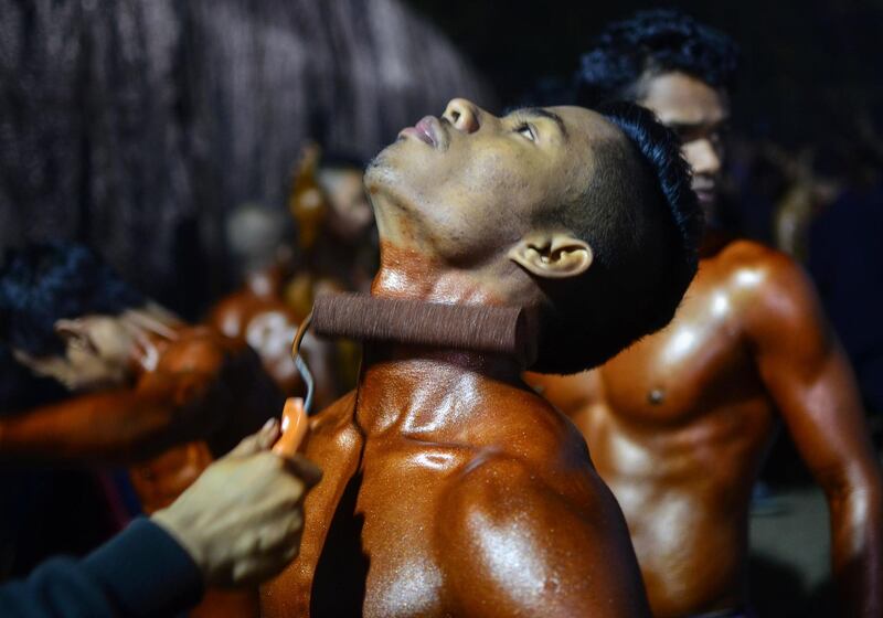 An Indian bodybuilding competitor gets a coat of fake tan rolled on to him ahead of a compeition in Dibrugarh in India's northeast Assam state. AFP Photo